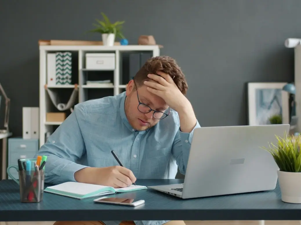 Stressed office worker checking the time and planning to leave work early with a subtle excuse